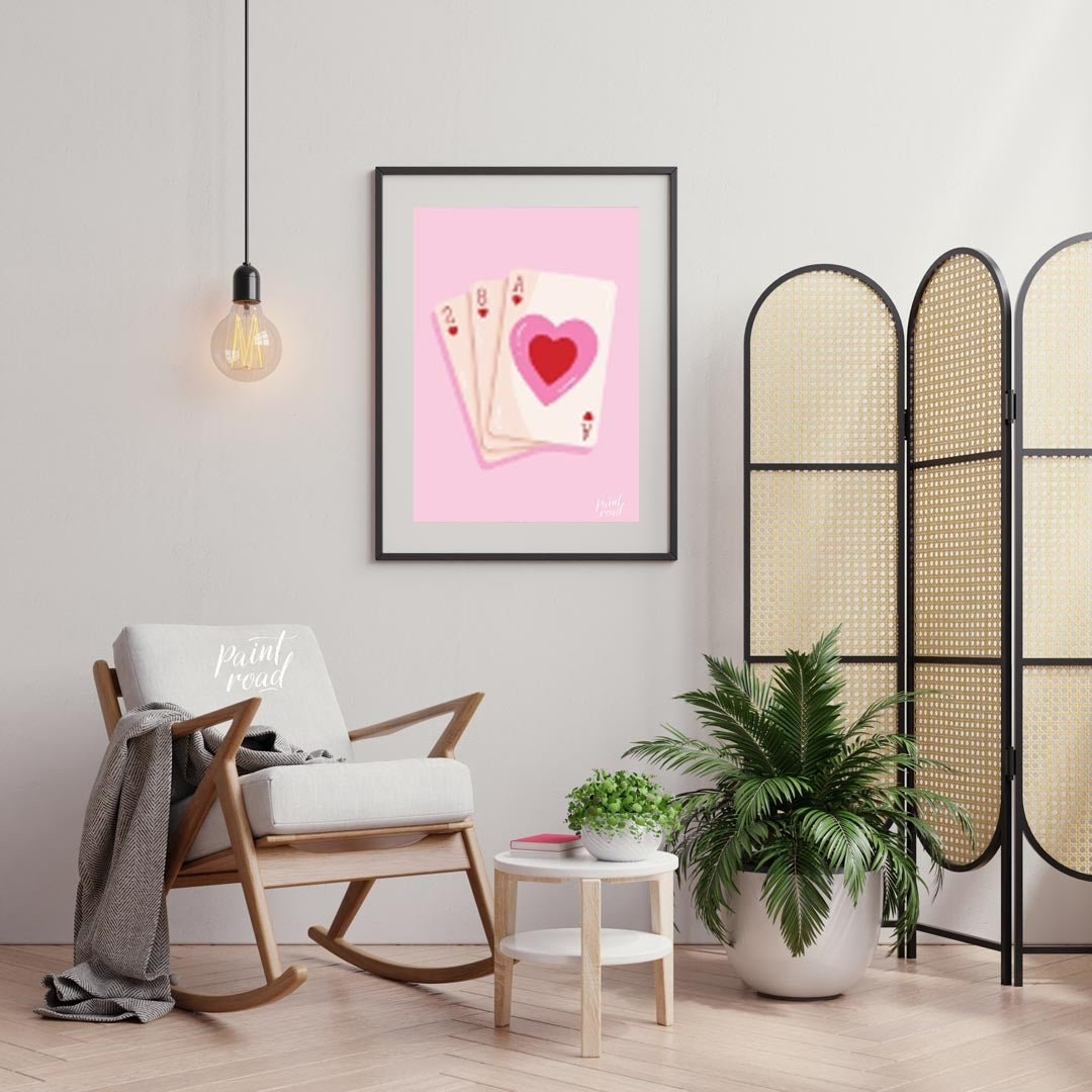 This charming and subtly romantic print features a hand of playing cards against a soft pink backgr… for living room