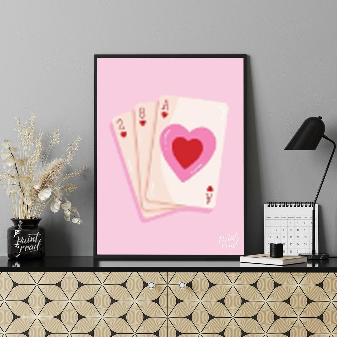 This charming and subtly romantic print features a hand of playing cards against a soft pink backgr… for office