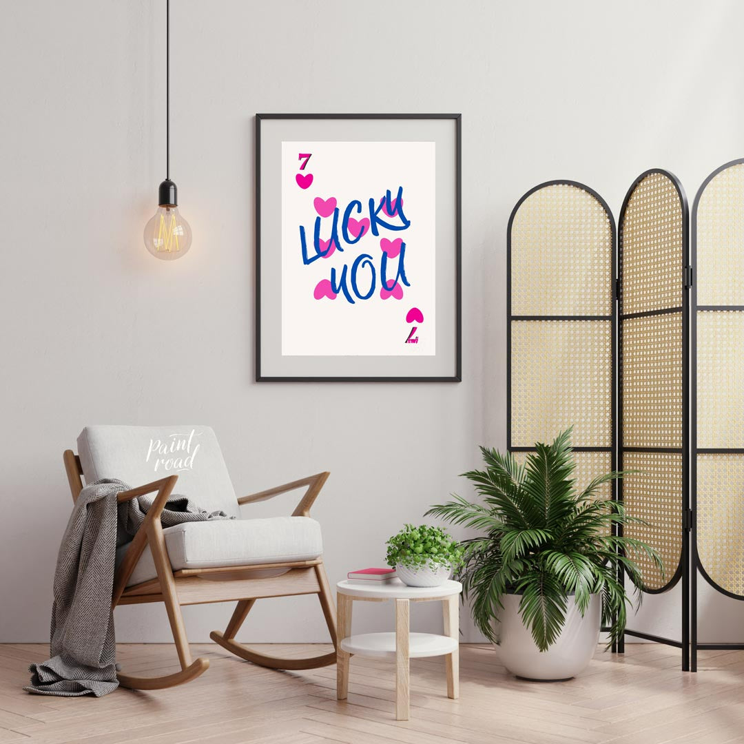 This playful and charming print features the phrase “LUCKY YOU” in a bold, hand-drawn blue script, … for living room
